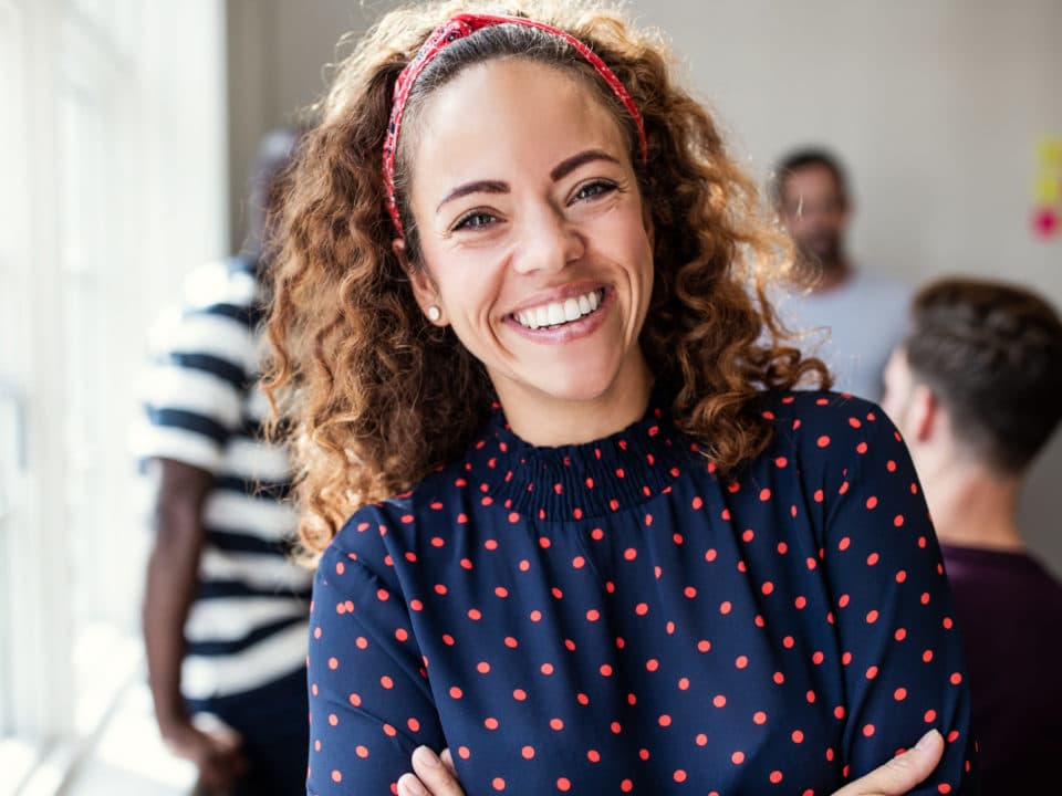 Curly haired woman smiling in polka dot shirt teeth whitening cosmetic dentist washington mi
