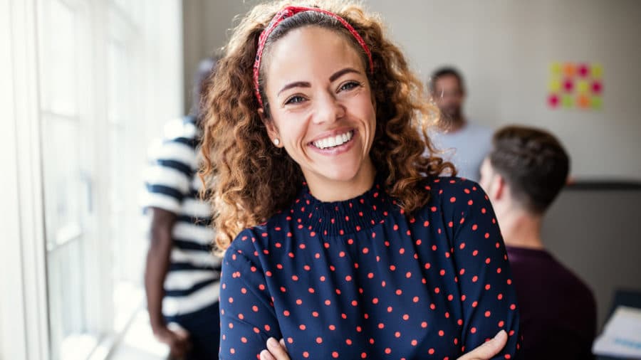Curly haired woman smiling in polka dot shirt teeth whitening cosmetic dentist washington mi