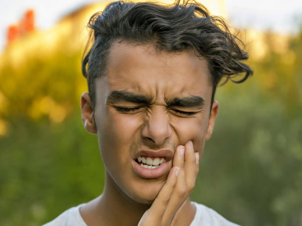 Young man holding face in pain Washington MI dentist
