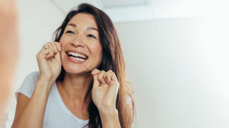 Woman flossing at dental implant dentist in Washington MI